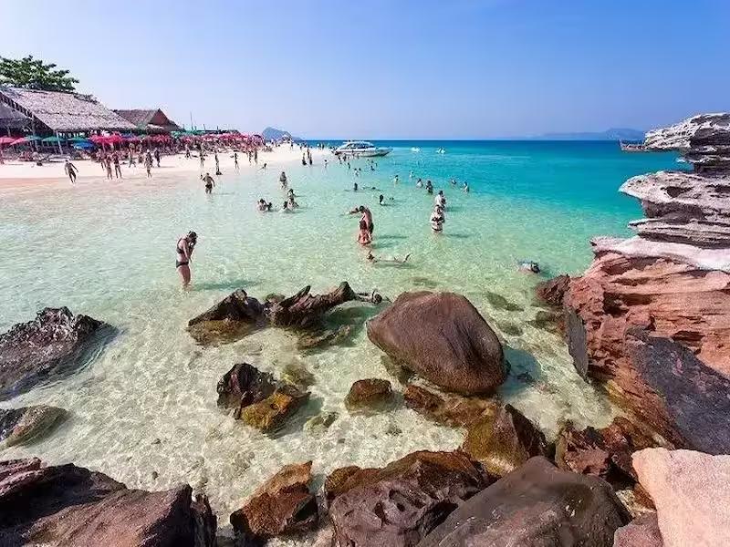 Relaxing on the beach at Khai Nai Island with loungers and umbrellas, perfect for a day trip from Phuket