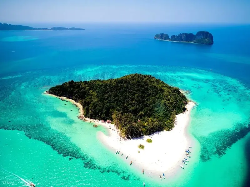 Speedboat approaching Bamboo Island's white sand beach with palm trees in Phi Phi archipelago