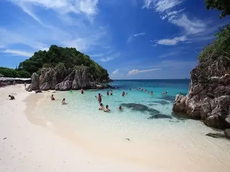 Tourists feeding colorful tropical fish in the crystal clear shallow waters of Khai Island, Thailand