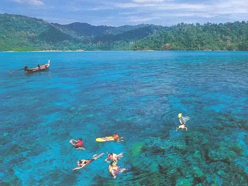 Tourists snorkeling in the clear blue water of the Surin Islands